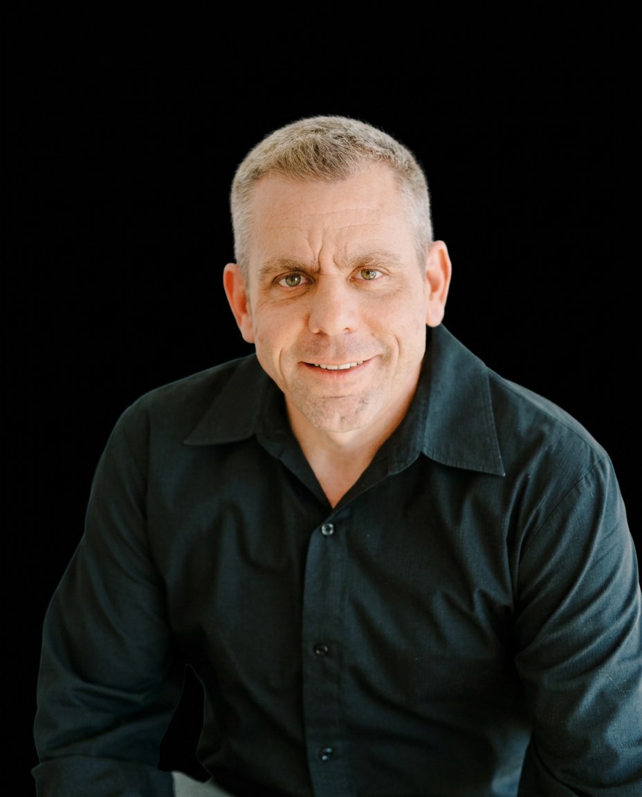 Troy Moultrie, BlackSalt Group founding partner leading divorce, probate and luxury listings, smiling in a black button-up shirt against a black studio backdrop.
