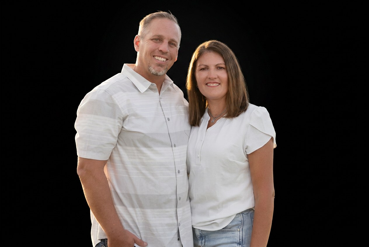 Brady Breinholt, BlackSalt Group founding partner, standing with his wife against a black studio backdrop.