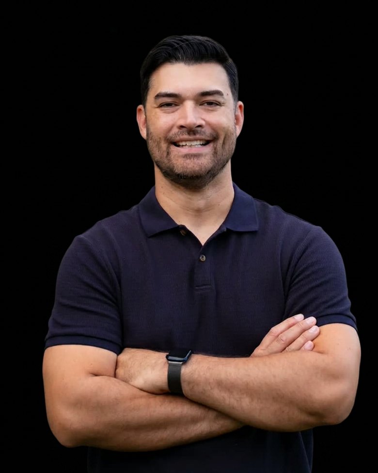 Brandon Savaiinaea, BlackSalt Group partner, smiling with arms crossed in a navy polo against a black backdrop.